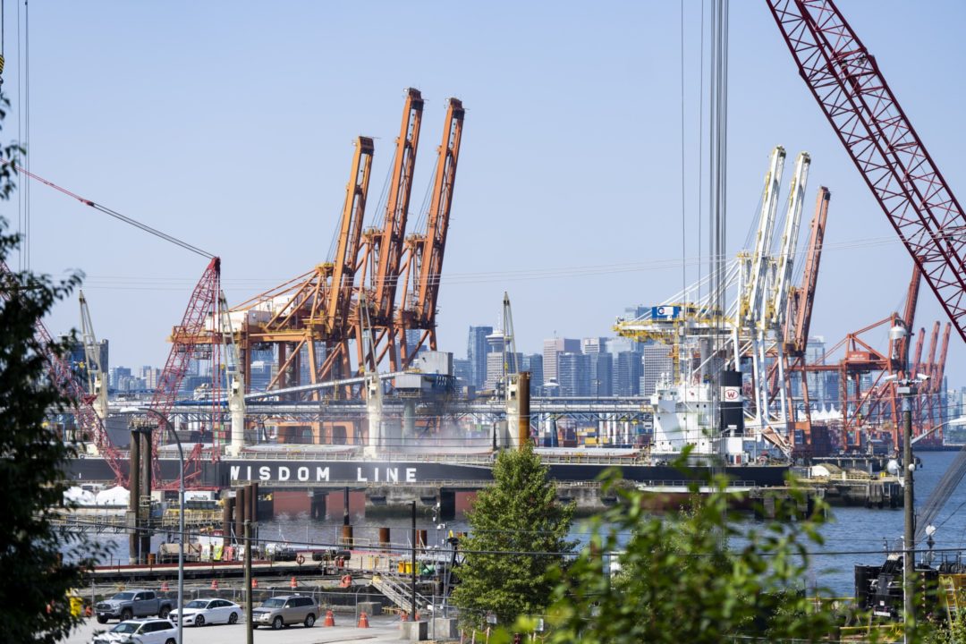 SHIPS ARE TETHERED AT A LARGE DOCK, WITH CRANES