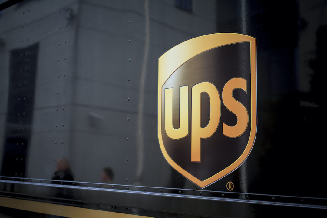 A CLOSE-UP OF THE UPS LOGO CAN BE SEEN ON THE SIDE OF A BROWN VEHICLE