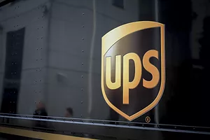 A CLOSE-UP OF THE UPS LOGO CAN BE SEEN ON THE SIDE OF A BROWN VEHICLE