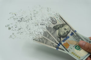 A PERSON IS HOLDING THREE 100 DOLLAR BILLS THAT ARE DISINTEGRATING.
