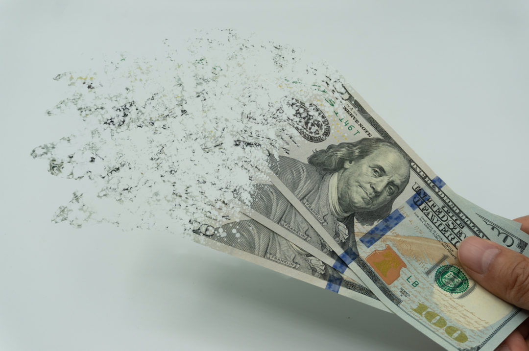 A PERSON IS HOLDING THREE 100 DOLLAR BILLS THAT ARE DISINTEGRATING.