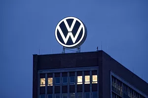 A LARGE VOLKSWAGEN LOGO IS HANGING ABOVE AN OFFICE BUILDING AT NIGHT.