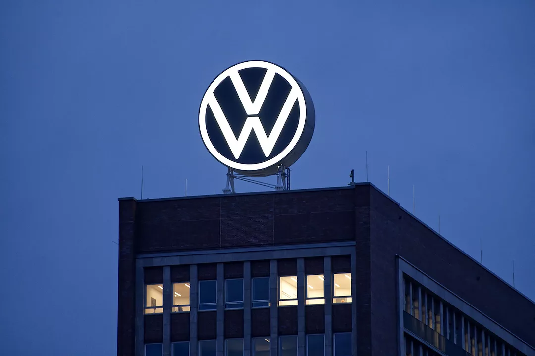 A LARGE VOLKSWAGEN LOGO IS HANGING ABOVE AN OFFICE BUILDING AT NIGHT.