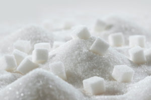 SEVERAL SUGAR CUBES SIT ON TOP SMALL PILES OF SUGAR.