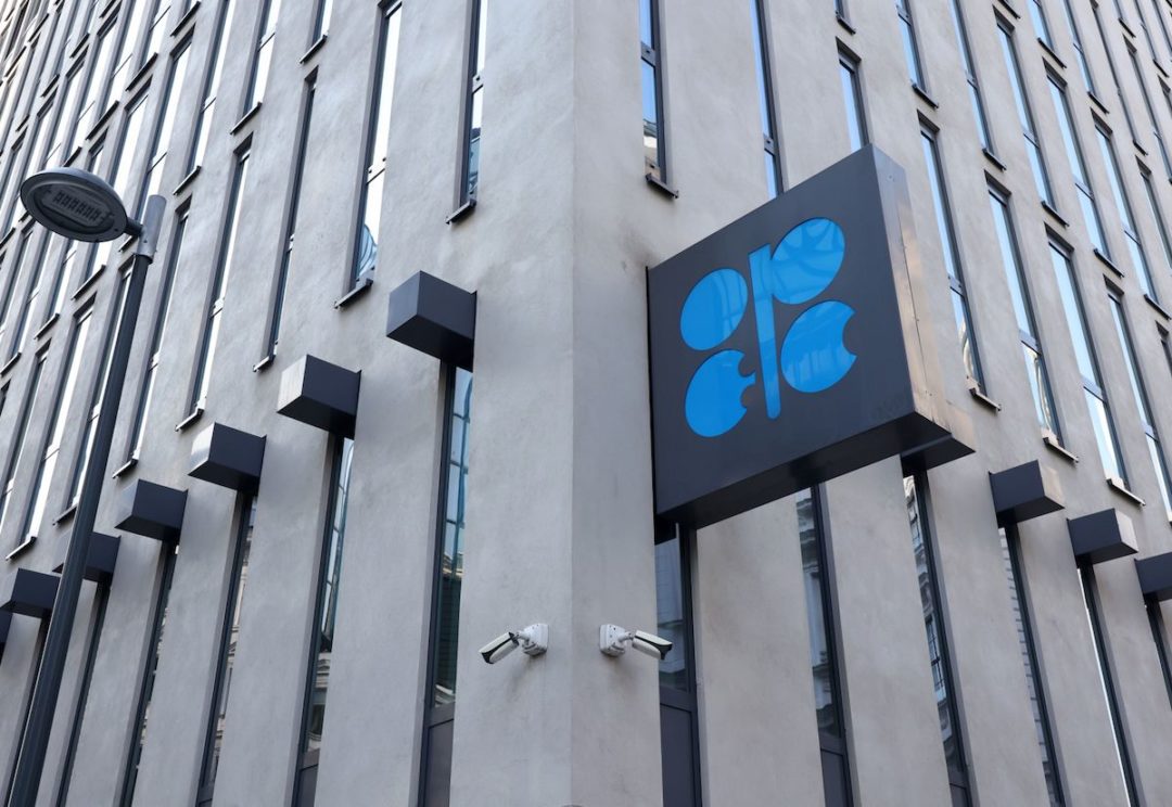 A SMALL BLACK AND BLUE OPEC SIGN HANGS ON THE SIDE OF AN OFFICE BUILDING.