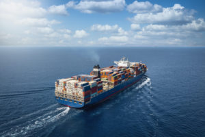 A LARGE CONTAINER SHIP CARRYING MULTI-COLORED CONTAINERS TRAVELS ON A CALM OCEAN.
