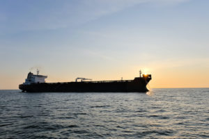 A CRUDE OIL TANKER SITS ON THE SEA AT SUNSET.