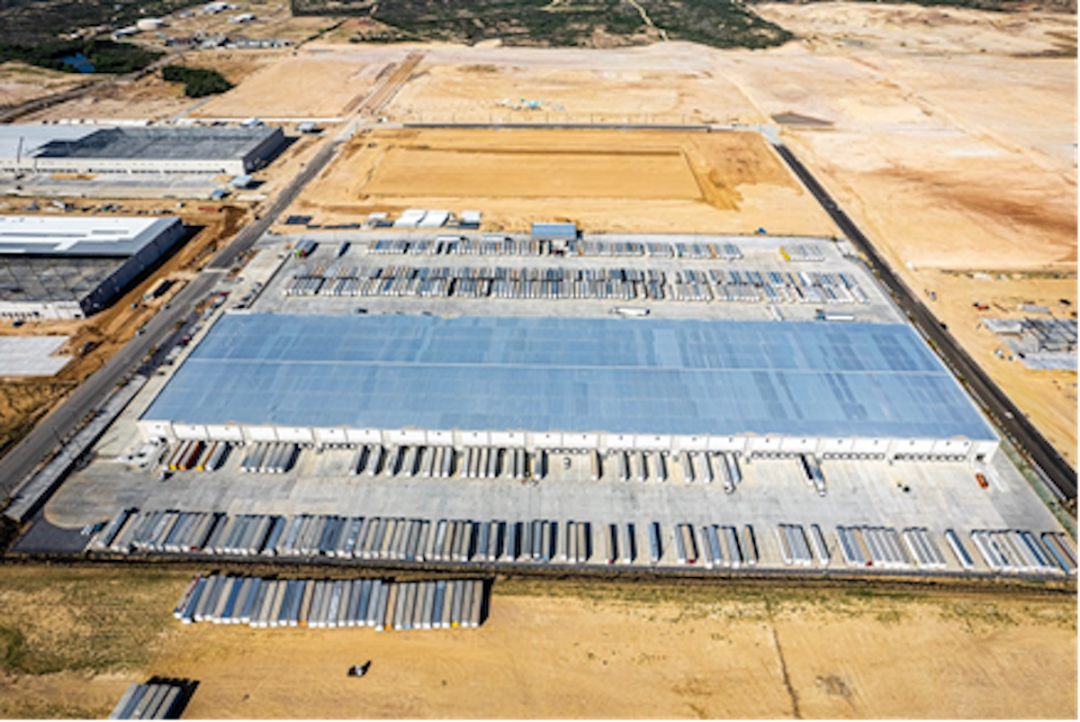 AN AERIAL VIEW OF A LARGE LOGISTICS FACILITY WITH A PARKING LOT FULL OF TRUCKS.