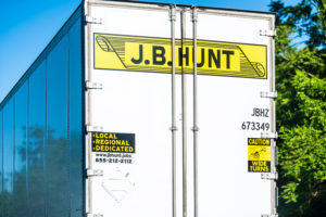 A YELLOW J.B. HUNT LOGO CAN BE SEEN ON THE BACK OF A TRUCK TRAILER.