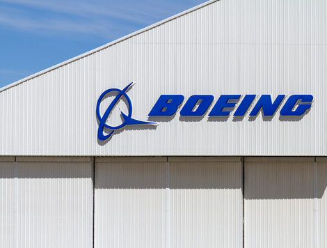 THE BOEING COMPANY LOGO CAN BE SEEN ON THE WALL OF A BUILDING WITH A BLUE SKY IN THE BACKGROUND.