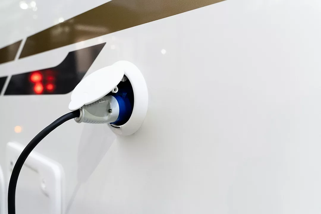 A CHARGER IS PLUGGED INTO A WHITE AND BLACK VEHICLE.