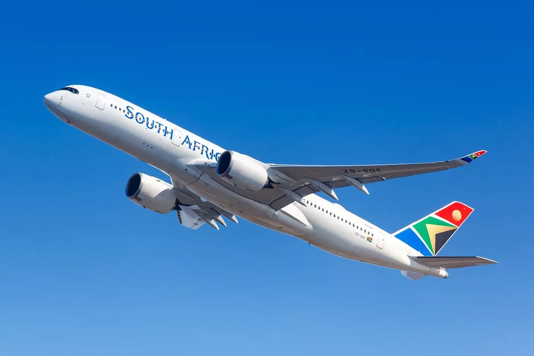 AN AIRPLANE WITH THE WORDS SOUTH AFRICAN ON THE SIDE AND A BRIGHTLY COLORED TAIL SHOWING ELEMENTS OF THE SOUTH AFRICAN FLAG, FLIES ACROSS THE SKY510.jpg