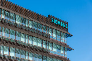 THE SIEMENS LOGO IS DISPLAYED ON THE CORNER OF A BROWN AND GLASS-COVERED OFFICE BUILDING.
