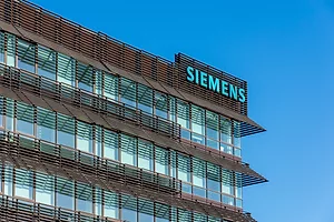 THE SIEMENS LOGO IS DISPLAYED ON THE CORNER OF A BROWN AND GLASS-COVERED OFFICE BUILDING.