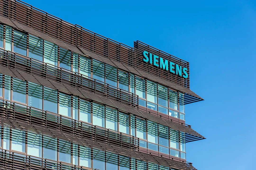 THE SIEMENS LOGO IS DISPLAYED ON THE CORNER OF A BROWN AND GLASS-COVERED OFFICE BUILDING.