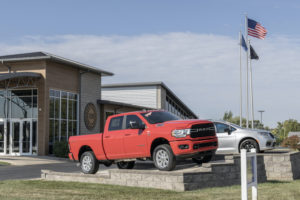 A RED GMC TRUCK IS PARKED IN FRONT OF A UAW OFFICE UNDER A CLOUDY BLUE SKY.