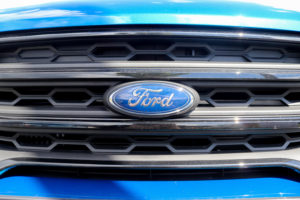 CLOSE-UP OF THE FORD LOGO ON THE GRILL OF A BLUE VEHICLE.