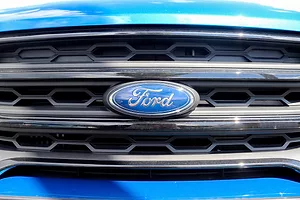 CLOSE-UP OF THE FORD LOGO ON THE GRILL OF A BLUE VEHICLE.