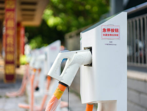 A ROW OF ELECTRIC VEHICLE CHARGING STATIONS HAS MANDARIN WRITING AND STICKERS ON THE SIDE OF IT