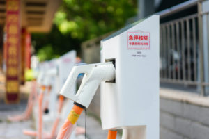 A ROW OF ELECTRIC VEHICLE CHARGING STATIONS HAS MANDARIN WRITING AND STICKERS ON THE SIDE OF IT