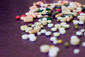 A CLOSE-UP OF VARIOUS PILLS ON A MAGENTA TABLE.
