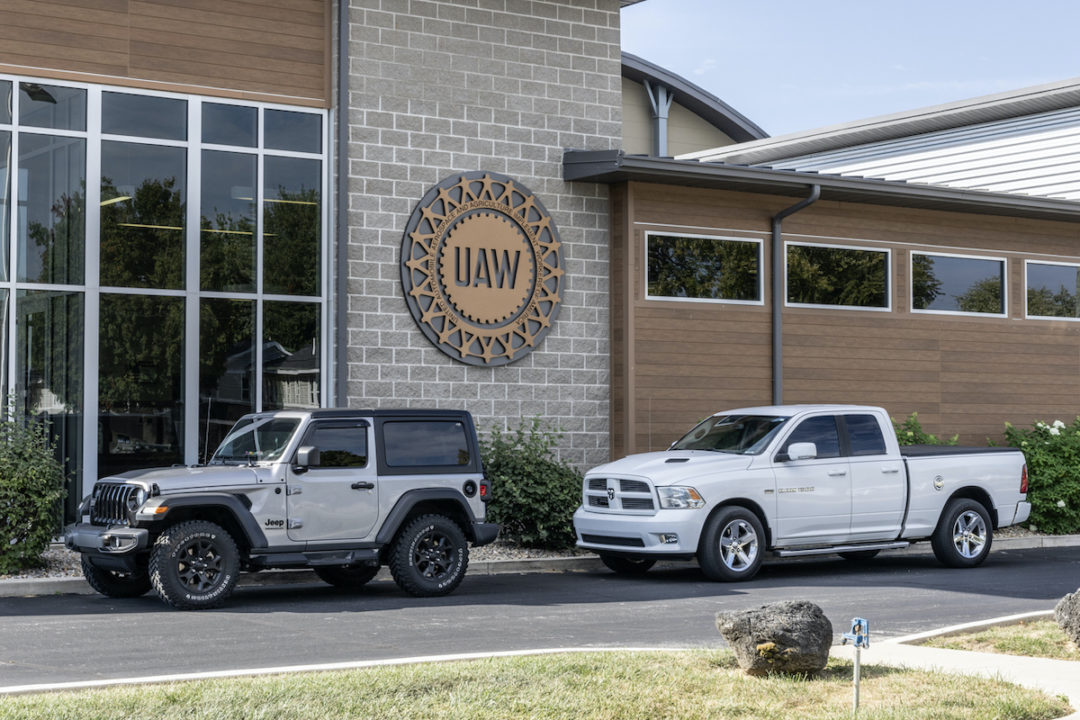 A JEEP AND A PICK-UP TRUCK ARE PARKED IN FRONT OF THE UAW OFFICE BUILDING.