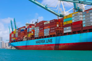 MANY SHIPPING CONTAINERS ARE BEING HELD ON A DOCKED MAERSK SHIP.