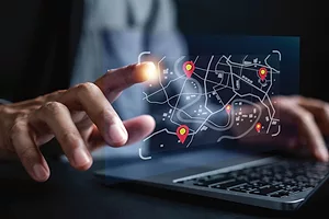 HANDS TYPE AT A COMPUTER, SURROUNDED BY GRAPHICS.