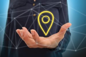A PERSON HOLDS IN THEIR HAND AN IMAGE OF A GEOLOCATION PIN.