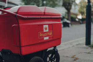 A RED DELIVERY TROLL ON THE STREETS OF LONDON HAS THE ROYAL MAIL LOGO ON IT.