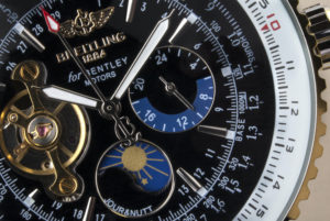 CLOSEUP OF A SILVER, BLUE AND GOLD BREITLING WATCH.