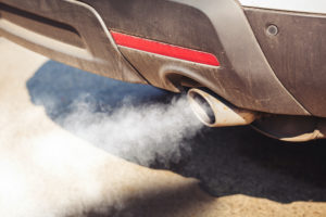 A CLOSE-UP OF SMOKE BILLOWING OUT OF A CAR'S TAILPIPE.