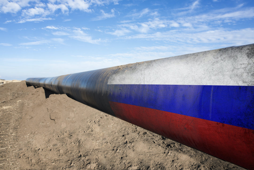 AN OIL PIPELINE SURROUNDED BY DIRT FADES INTO THE RUSSIAN FLAG.
