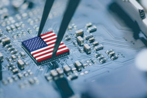 THE U.S. FLAG CAN BE SEEN ON THE TOP OF A GPU MICROCHIP THAT IS BEING PICKED UP WITH A PAIR OF TWEEZERS.
