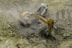 A DIGGER IN AN OPEN MINE IS SHROUDED IN DUST.