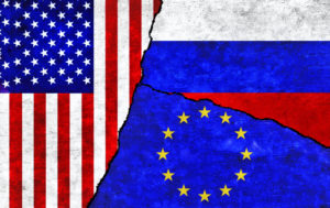 THE RUSSIAN, U.S. AND EU FLAGS ARE DIVIDED ON A TEXTURED WALL.