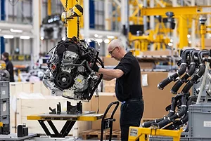 AN EMPLOYEE WORKS ON AN ENGINE INSIDE OF A FACTORY.