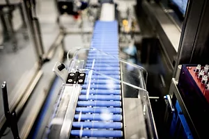 INJECTION PENS SIT ON A CONVEYOR BELT IN A FACTORY.