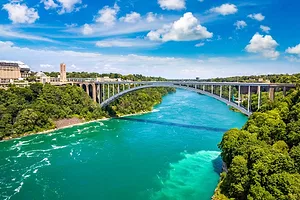 A SINGLE ARCH CONCRETE BRIDGE SPANS A BROAD RIVER