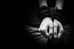 BLACK AND WHITE PHOTO OF A PERSON'S HANDS TIED UP WITH ROPE.