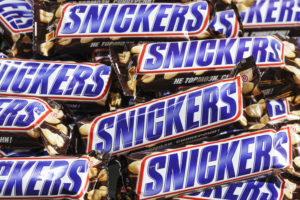 CLOSE-UP OF SEVERAL SNICKERS BARS NEXT TO AND ON TOP OF EACH OTHER.