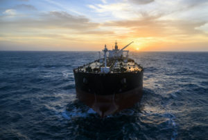 AN OIL TANKER SAILS ON THE OCEAN WHILE THE SUN SETS.