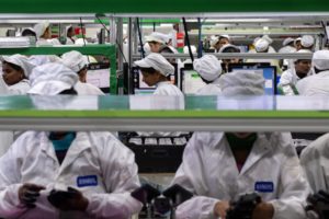 EMPLOYEES TEST MOBILE PHONES ON AN ASSEMBLY LINE.