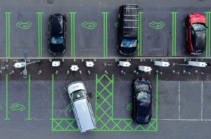 AERIAL VIEW OF ELECTRIC VEHICLES IN A PARKING LOT PLUGGED INTO CHARGERS