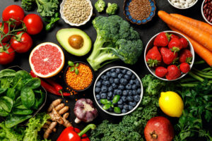 A COLORFUL ARRAY OF FRUITS, VEGETABLES AND OTHER SUPERFOODS IN FRONT OF A BLACK BACKGROUND.