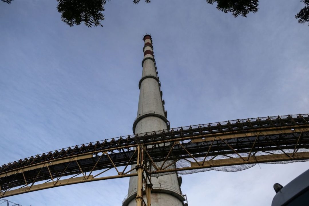 GROUND-VIEW OF A SMOKESTACK ATTACHED TO A THERMAL POWER STATION.