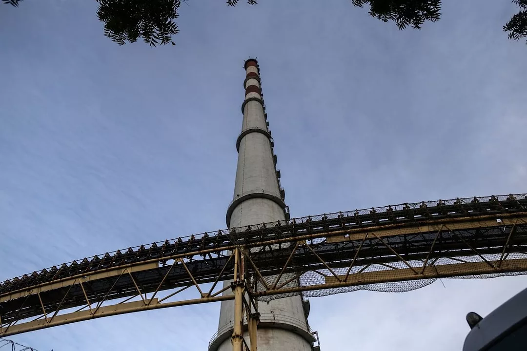 GROUND-VIEW OF A SMOKESTACK ATTACHED TO A THERMAL POWER STATION.
