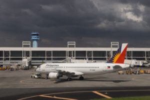 AN AIRPLANE SPORTING THE WORD PHILIPPINES, SITS ON THE TARMAC AT AN AIRPORT