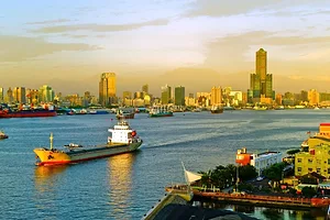 A SHIP MOTORS OUT OF A CITY HARBOR