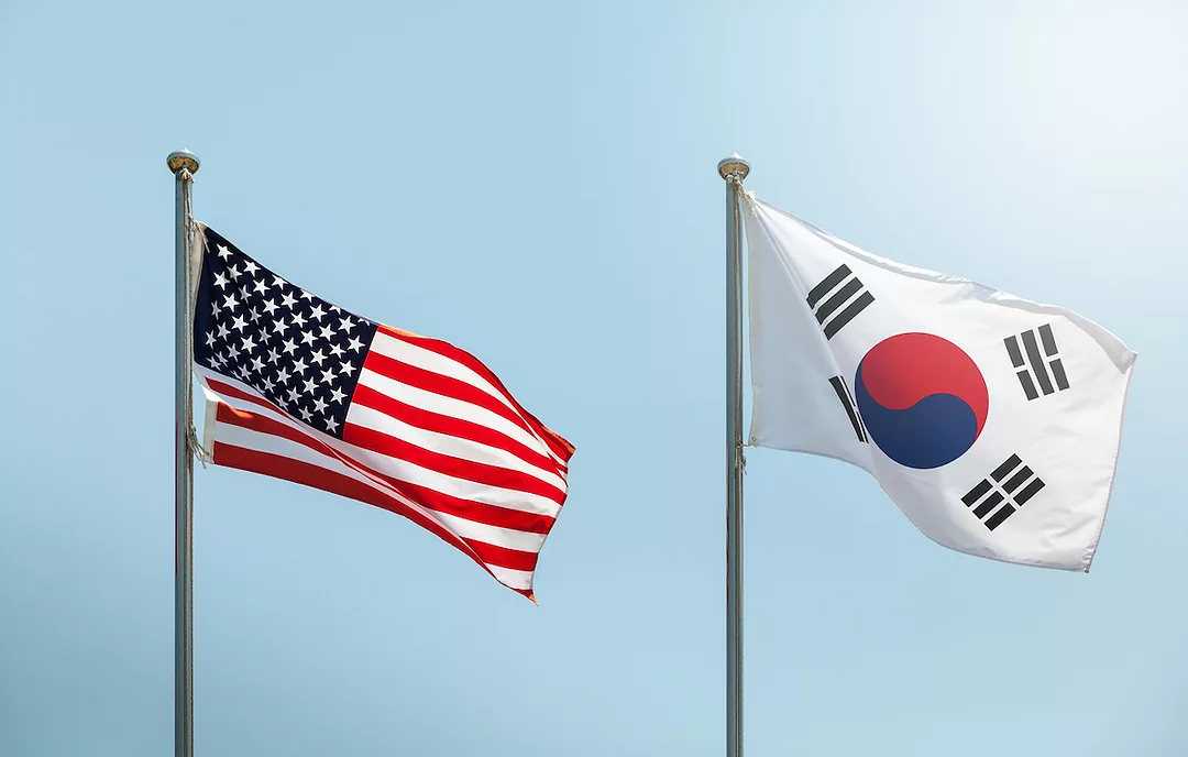 A U.S. FLAG WAVING IN THE WIND NEXT TO A SOUTH KOREAN FLAG.